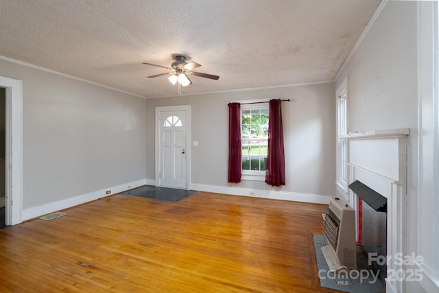 357 N Main St, Mount Pleasant, NC 28124 - foyer featuring ceiling fan, wood-type flooring, a textured ceiling, crown molding, and a fireplace with flush hearth