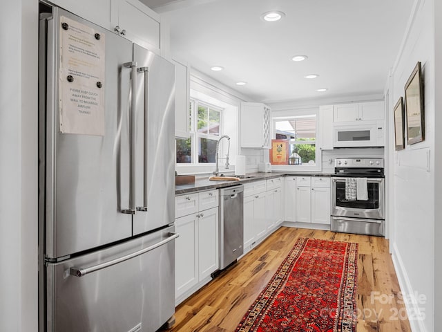 2784 Pea Ridge Rd, Mill Spring, NC 28756 - kitchen featuring appliances with stainless steel finishes, light wood finished floors, white cabinetry, recessed lighting, and dark countertops