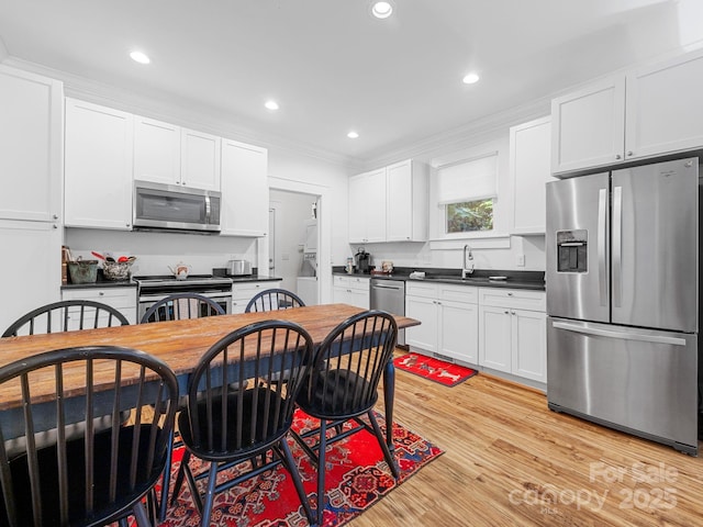 2784 Pea Ridge Rd, Mill Spring, NC 28756 - kitchen with stainless steel appliances, crown molding, dark countertops, white cabinetry, and light wood-type flooring