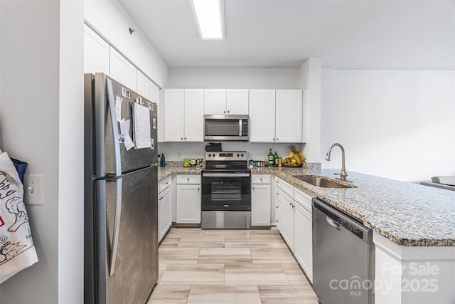 1315 E Blvd Unit 321, Charlotte, NC 28203 - kitchen featuring appliances with stainless steel finishes, a peninsula, light stone counters, and white cabinetry
