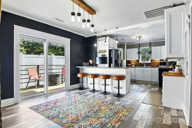 840 10th Street Blvd NW, Hickory, NC 28601 - kitchen featuring refrigerator with ice dispenser, light wood-style flooring, a textured ceiling, stainless steel microwave, and a breakfast bar