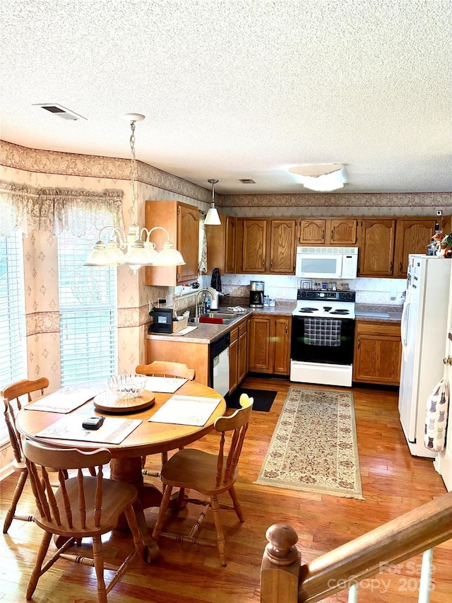 1902 Stonewyck Ave, Kannapolis, NC 28081 - kitchen with white appliances, wallpapered walls, a textured ceiling, brown cabinets, and light wood-type flooring