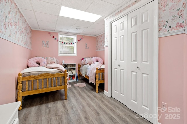 233 Church St, Ellenboro, NC 28040 - bedroom featuring wallpapered walls, light wood finished floors, a closet, and a paneled ceiling