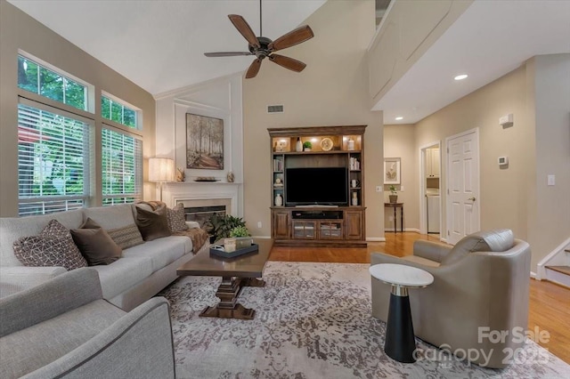9040 Scottsboro Dr, Huntersville, NC 28078 - living area featuring wood finished floors, a ceiling fan, a towering ceiling, and a glass covered fireplace