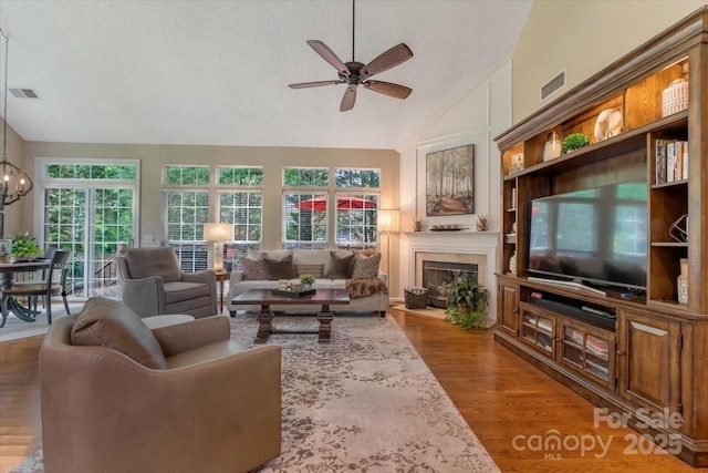 9040 Scottsboro Dr, Huntersville, NC 28078 - living room featuring vaulted ceiling, ceiling fan, a textured ceiling, a fireplace with flush hearth, and wood finished floors