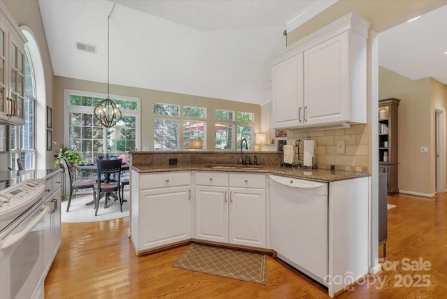 9040 Scottsboro Dr, Huntersville, NC 28078 - kitchen featuring white appliances, a peninsula, white cabinetry, light stone counters, and lofted ceiling