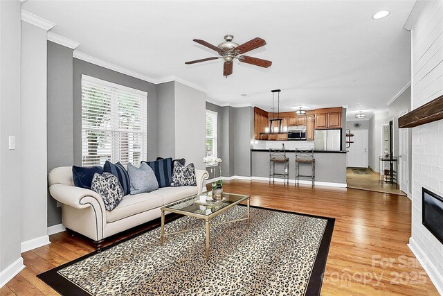 921 NE Dr, Davidson, NC 28036 - living room with light wood-type flooring, a ceiling fan, a fireplace, crown molding, and recessed lighting