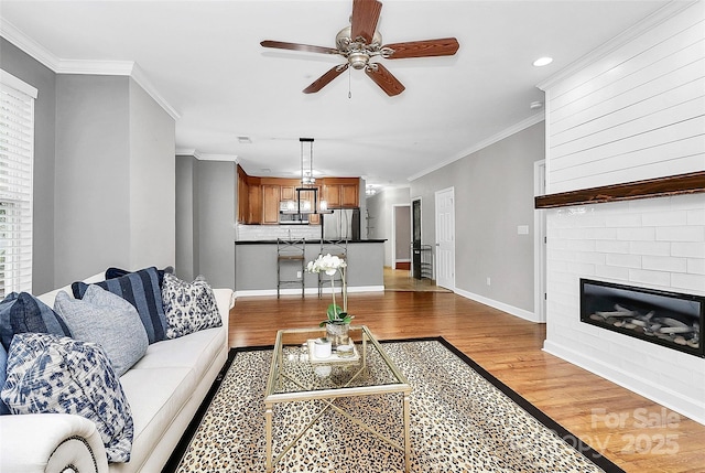 921 NE Dr, Davidson, NC 28036 - living area featuring light wood-type flooring, a ceiling fan, crown molding, a large fireplace, and recessed lighting