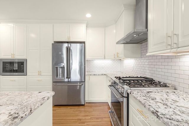 4526 Longwood Dr, Charlotte, NC 28209 - kitchen with appliances with stainless steel finishes, wall chimney exhaust hood, white cabinets, light wood finished floors, and recessed lighting