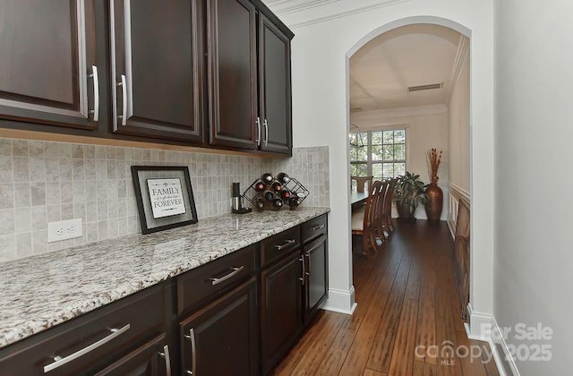 3913 Widgeon Way, Waxhaw, NC 28173 - kitchen featuring dark wood-type flooring, dark brown cabinets, arched walkways, light stone countertops, and decorative backsplash