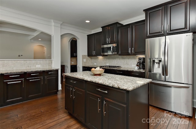 3913 Widgeon Way, Waxhaw, NC 28173 - kitchen featuring stainless steel appliances, decorative backsplash, arched walkways, dark wood-style flooring, and light stone countertops