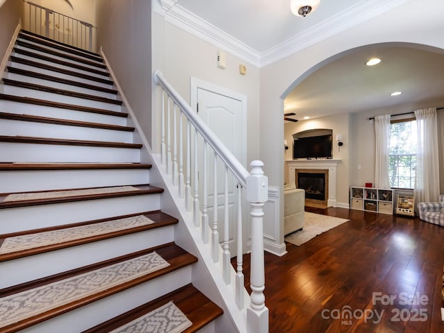 12928 Windy Lea Ln, Huntersville, NC 28078 - stairs featuring ceiling fan, a fireplace with flush hearth, hardwood / wood-style floors, ornamental molding, and arched walkways
