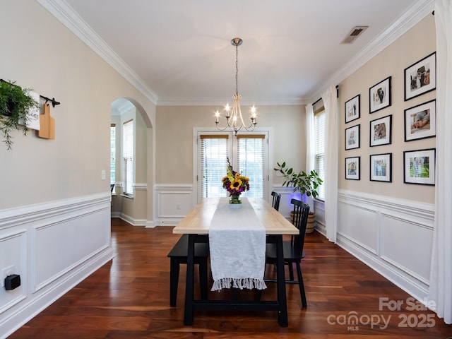12928 Windy Lea Ln, Huntersville, NC 28078 - dining area featuring a chandelier, arched walkways, crown molding, a wainscoted wall, and a decorative wall