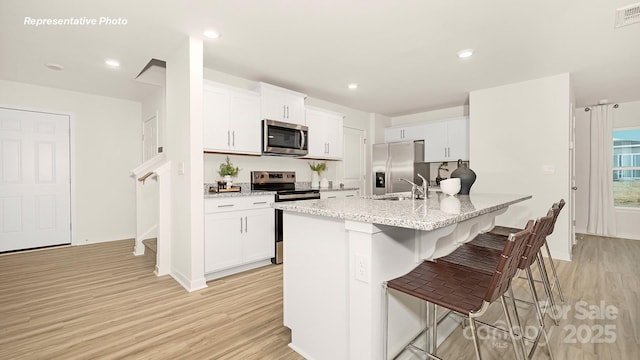 12019 Zazu Way, Charlotte, NC 28215 - kitchen featuring stainless steel appliances, light wood-style floors, a kitchen breakfast bar, white cabinetry, and recessed lighting