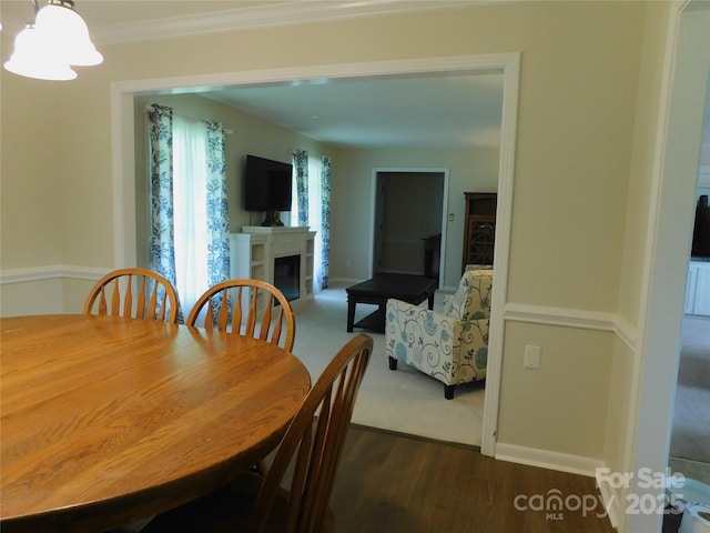 714 Shady Dr, Albemarle, NC 28001 - dining room featuring a glass covered fireplace, dark wood-style floors, ornamental molding, and a chandelier