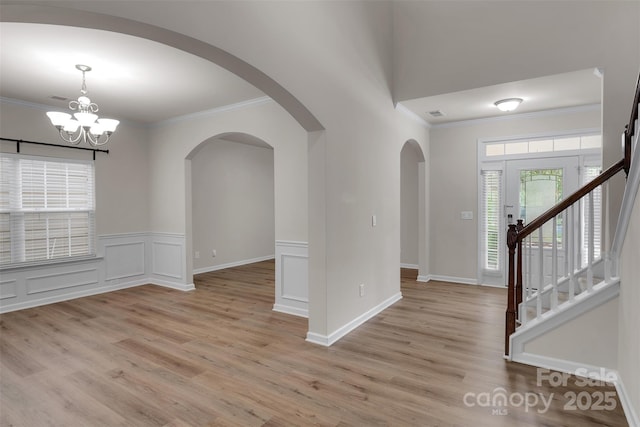 11538 Ardrey Crest Dr, Charlotte, NC 28277 - entrance foyer with crown molding, a chandelier, arched walkways, light wood finished floors, and a wainscoted wall