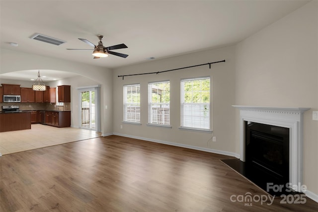 11538 Ardrey Crest Dr, Charlotte, NC 28277 - unfurnished living room featuring arched walkways, a ceiling fan, plenty of natural light, and light wood-style flooring