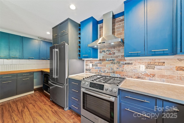 344 Hemlock Springs Trl, Weaverville, NC 28787 - kitchen with wall chimney range hood, appliances with stainless steel finishes, blue cabinets, tasteful backsplash, and recessed lighting