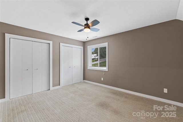 344 Hemlock Springs Trl, Weaverville, NC 28787 - unfurnished bedroom with two closets, light colored carpet, a ceiling fan, and a textured ceiling
