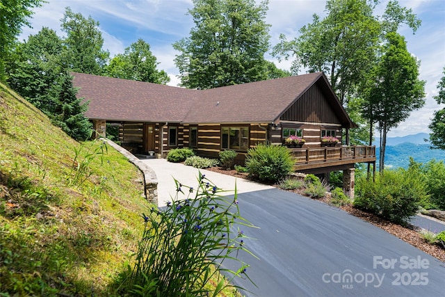 242 Anisidi Trl, Maggie Valley, NC 28751 - view of front of home featuring roof with shingles, a deck with mountain view, and driveway