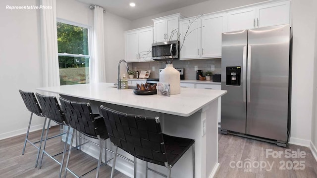 780 14th Avenue Ct NE, Hickory, NC 28601 - kitchen featuring appliances with stainless steel finishes, white cabinets, light countertops, a center island with sink, and light wood finished floors