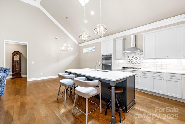6107 Gold Springs Way, Denver, NC 28037 - kitchen with wall chimney range hood, a chandelier, a kitchen island with sink, a kitchen breakfast bar, and decorative backsplash