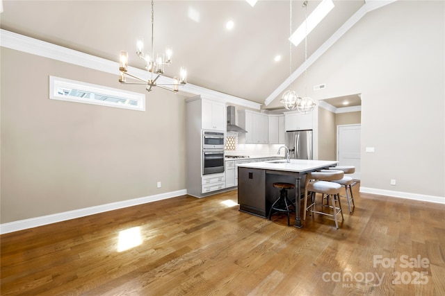 6107 Gold Springs Way, Denver, NC 28037 - kitchen featuring a chandelier, stainless steel appliances, wall chimney range hood, a kitchen island with sink, and tasteful backsplash