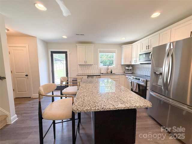 103 Springway Dr, Kannapolis, NC 28081 - kitchen featuring appliances with stainless steel finishes, tasteful backsplash, a center island, white cabinets, and light stone counters