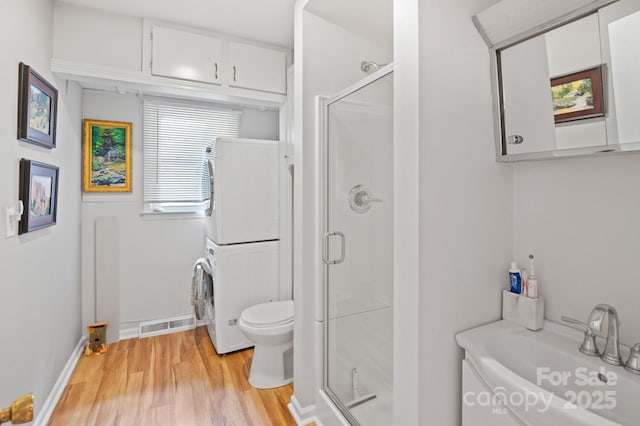 4 Sourwood Ln E, Asheville, NC 28805 - bathroom featuring stacked washer / dryer, a stall shower, and wood finished floors
