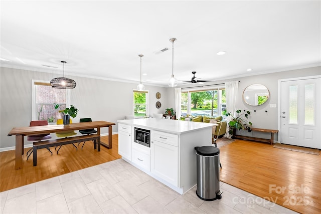 2919 Dunaire Dr, Charlotte, NC 28205 - kitchen featuring built in microwave, crown molding, light countertops, ceiling fan, and white cabinets