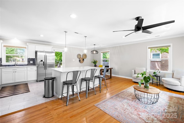 2919 Dunaire Dr, Charlotte, NC 28205 - kitchen featuring stainless steel fridge with ice dispenser, a kitchen breakfast bar, white cabinetry, a kitchen island, and recessed lighting
