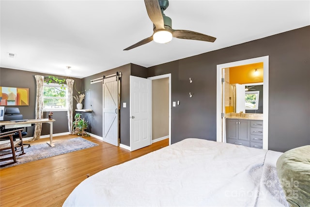 2919 Dunaire Dr, Charlotte, NC 28205 - bedroom featuring a barn door, wood finished floors, a desk, connected bathroom, and ceiling fan