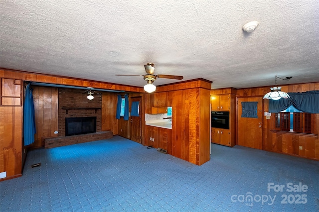 1216 Manchester Ln, Charlotte, NC 28227 - unfurnished living room featuring wood walls, carpet, a fireplace, a ceiling fan, and a textured ceiling