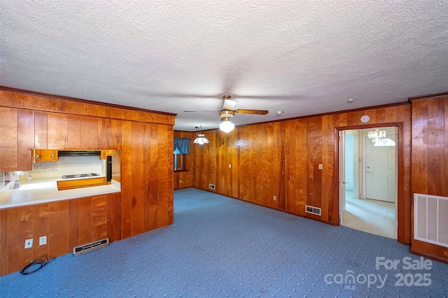 1216 Manchester Ln, Charlotte, NC 28227 - unfurnished living room featuring ceiling fan, wood walls, dark colored carpet, a textured ceiling, and crown molding