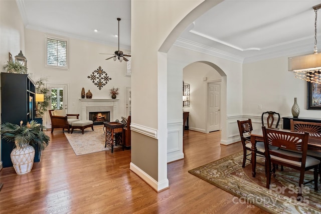 9027 Kirkley Ct, Charlotte, NC 28277 - dining room with a ceiling fan, wood finished floors, a fireplace, arched walkways, and crown molding