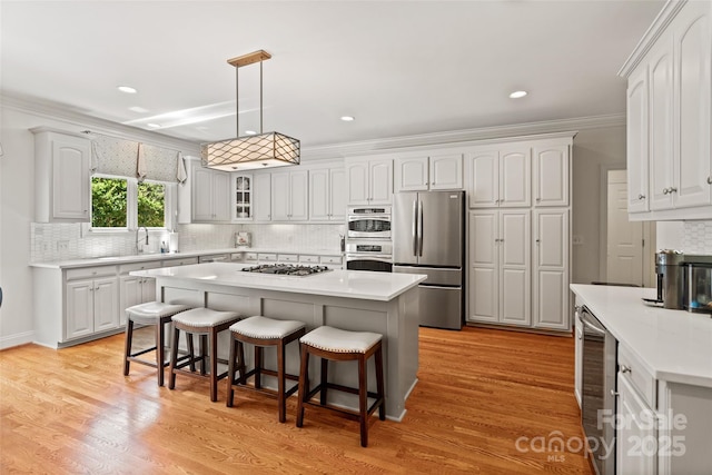 9027 Kirkley Ct, Charlotte, NC 28277 - kitchen featuring appliances with stainless steel finishes, a kitchen breakfast bar, decorative backsplash, a center island, and glass insert cabinets