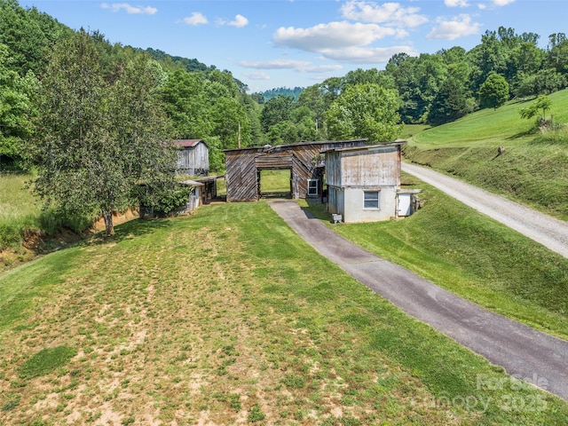 244 Carl Fox Rd, Burnsville, NC 28714 - view of green lawn with an outdoor structure, a barn, driveway, and a forest view