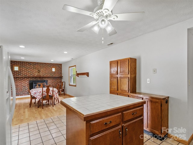244 Carl Fox Rd, Burnsville, NC 28714 - kitchen with white refrigerator with ice dispenser, tile countertops, light tile patterned floors, a fireplace, and a ceiling fan