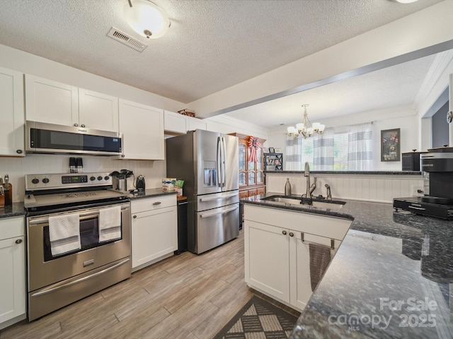 1252 Winding Path Rd, Lake Wylie, SC 29710 - kitchen with stainless steel appliances, a chandelier, a textured ceiling, dark stone countertops, and white cabinets