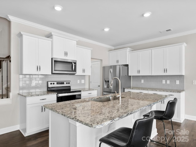 567 Big Sur Loop, Asheville, NC 28806 - kitchen featuring appliances with stainless steel finishes, decorative backsplash, a center island with sink, a breakfast bar area, and white cabinets