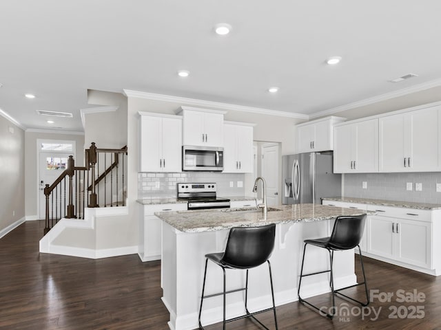 567 Big Sur Loop, Asheville, NC 28806 - kitchen with stainless steel appliances, a breakfast bar area, decorative backsplash, a center island with sink, and ornamental molding