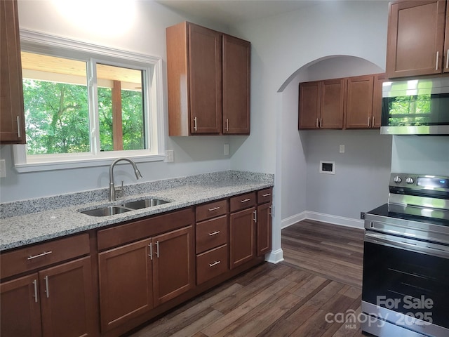 94 James St SW, Concord, NC 28025 - kitchen featuring stainless steel appliances, dark wood finished floors, light stone counters, and arched walkways