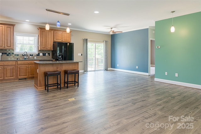 106 Beaver Dam Dr, Mills River, NC 28759 - kitchen featuring black refrigerator with ice dispenser, a kitchen island, a ceiling fan, wood finished floors, and backsplash