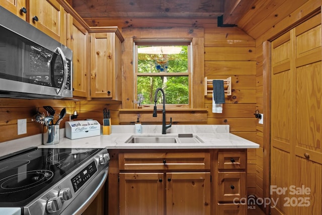 83 Log Cabin Dr, Maggie Valley, NC 28751 - kitchen with appliances with stainless steel finishes, wood walls, light stone counters, and brown cabinets