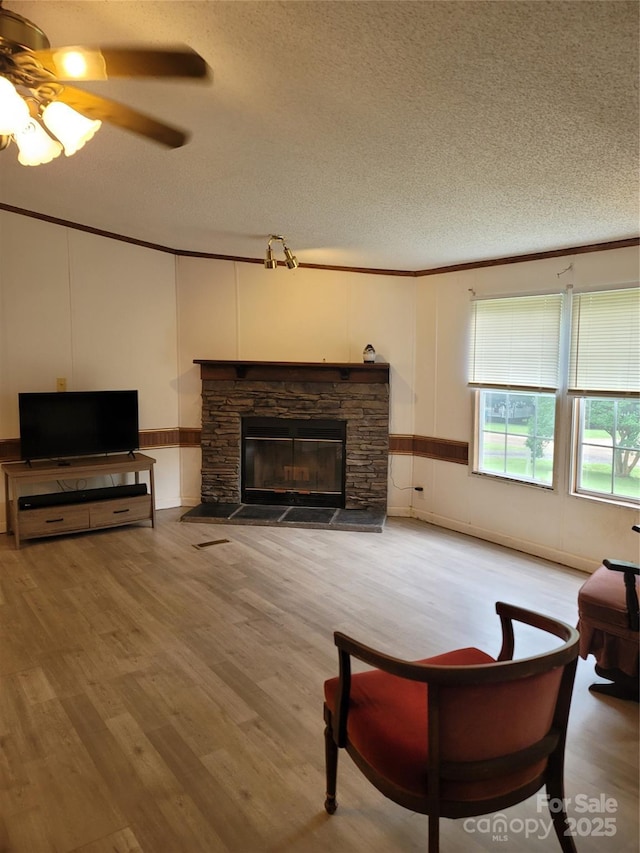 111 Crystal Creek Dr, China Grove, NC 28023 - living area with a textured ceiling, light wood finished floors, a fireplace, ornamental molding, and a ceiling fan