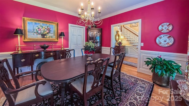 1240 Fawn Ridge Rd NW, Concord, NC 28027 - dining area with a chandelier, stairs, a wainscoted wall, wood finished floors, and ornamental molding
