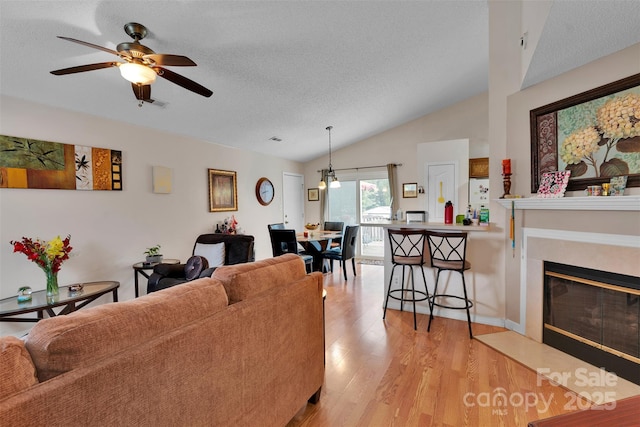 15248 Pangborn Pl, Charlotte, NC 28278 - living area featuring lofted ceiling, a textured ceiling, light wood-style floors, a ceiling fan, and a fireplace with flush hearth