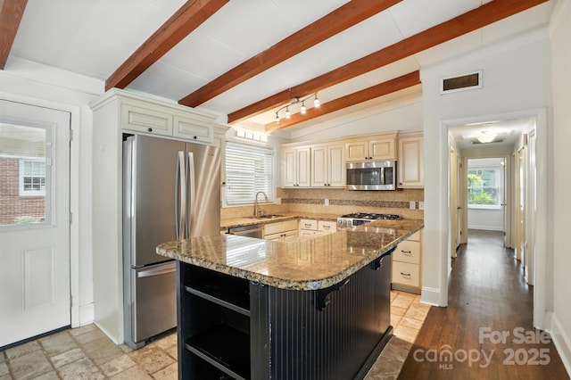 5229 Milford Rd, Charlotte, NC 28210 - kitchen featuring appliances with stainless steel finishes, light stone counters, a kitchen island, cream cabinetry, and backsplash