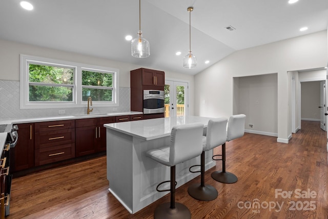 1115 Sides Rd, Salisbury, NC 28146 - kitchen with stainless steel oven, lofted ceiling, a breakfast bar area, decorative backsplash, and light countertops