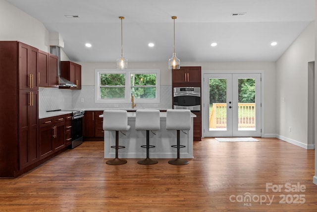 1115 Sides Rd, Salisbury, NC 28146 - kitchen with stainless steel appliances, lofted ceiling, decorative backsplash, a breakfast bar area, and wood finished floors